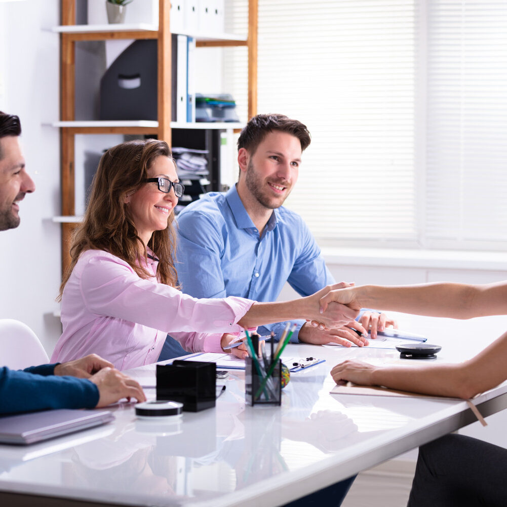 Smiling,Young,Businesswoman,Shaking,Hands,With,Female,Executive,At,Job